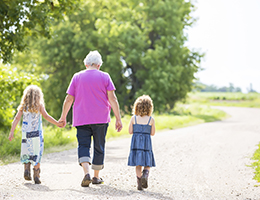 Grandmother walking outside in the sun with her two granddaughters.