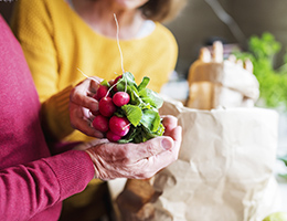 One person hands another a bunch of radishes.