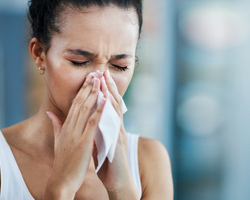 A woman sneezes into a tissue