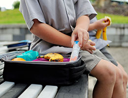 A child pulls an epi pen from a lunchbox. 