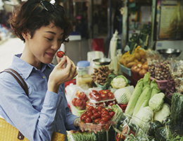 A woman at a farmers market holds cherry tomatoes. 
