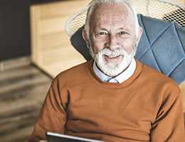 A smiling older man sitting in a chair.