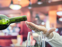 A hand extended over a wineglass signaling a waiter not to fill it.