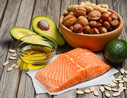 Fish, oil, avocados, seeds and nuts on a wood table.