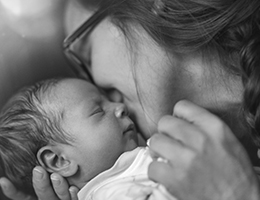 A mom kisses her sleeping baby on the cheek.