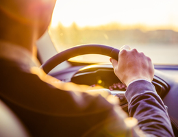 A man grips the steering wheel of a car.