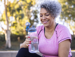 A woman drinks from a reusable water bottle.