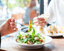 Close-up of a forkful of salad above a restaurant salad bowl.