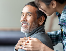 A seated man smiles over his shoulder at a woman behind him.
