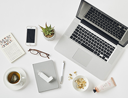 A laptop, cellphone, cup of tea, notebook and inhaler.