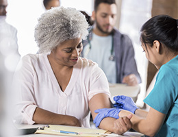 An older woman gets her arm swabbed before a vaccine.