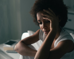 A tired woman holds a hand to her head.