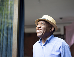 A smiling black man in a hat. 