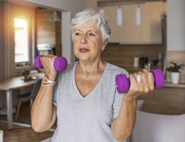 A woman holds up a pair of hand weights.